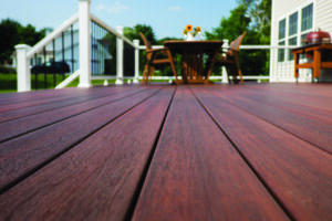 close up image of dark brown deck lumber, installed in a deck with white railing